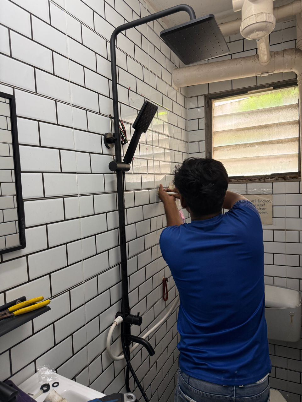 Rain shower being fitted in a tiled bathroom